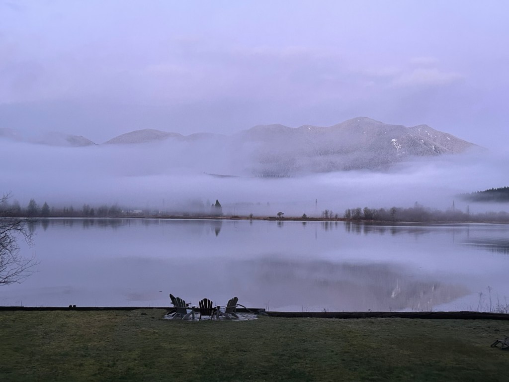 Early morning view of a bay with a hills rising on the other side enshrouded in fog
